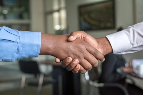 Business Meeting | CAQA Creative Two people shake hands during a business meeting, representing collaboration in creative arts.