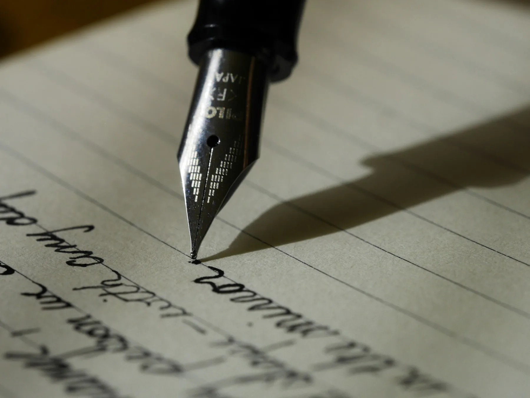 A fountain pen creates beautiful calligraphy on lined paper, showcasing creative writing skills.