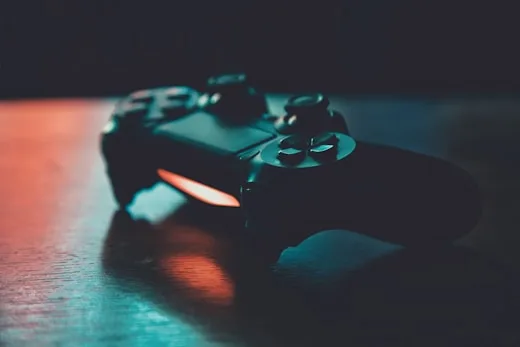Gaming Controller | CAQA Creative A black gaming controller sits on a surface with vibrant rgb lights, showcasing creative arts technology.