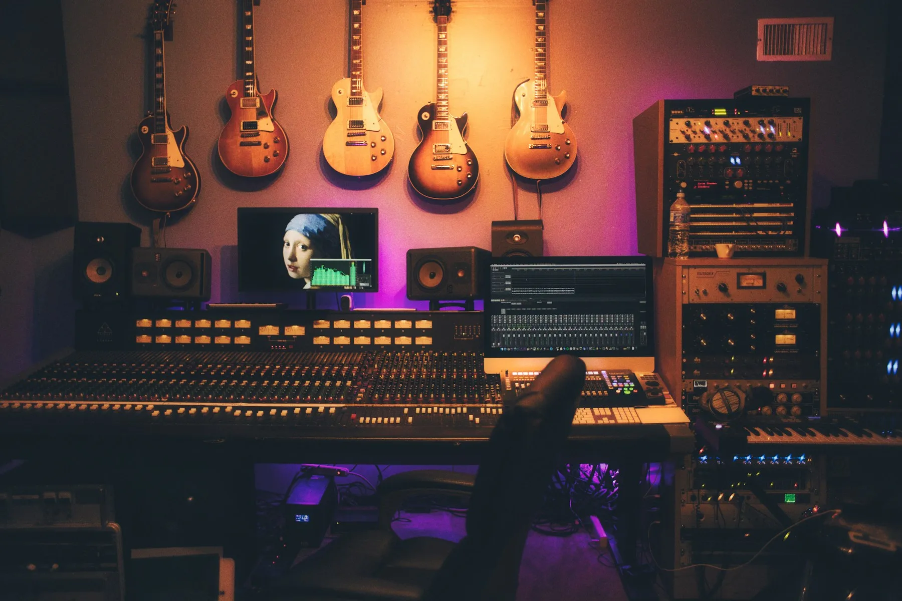 A recording studio with guitars and a mixing console showcases creative music production services at CAQA Creative.