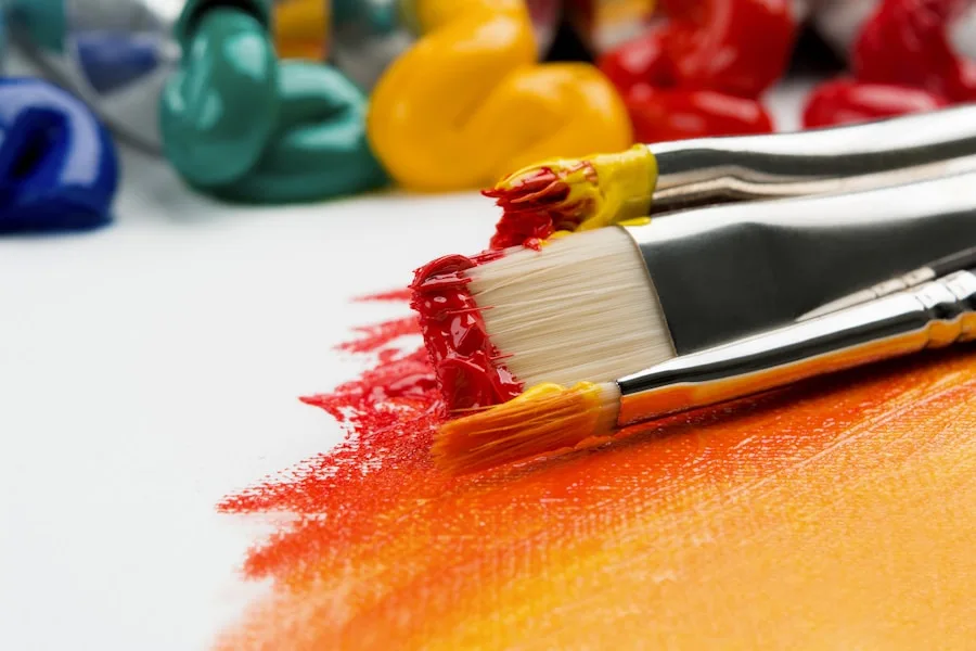 Paintbrushes and acrylic paint rest on a canvas, showcasing visual arts supplies.
